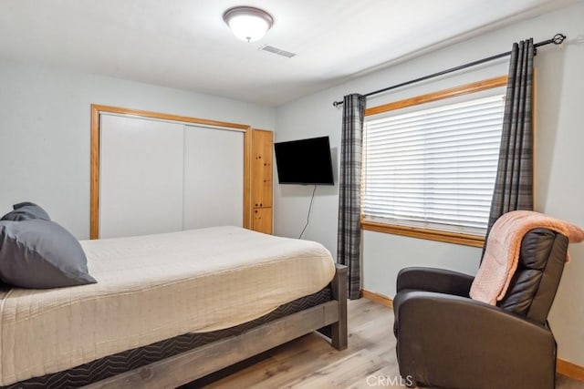 bedroom with baseboards, visible vents, a closet, and light wood-style flooring