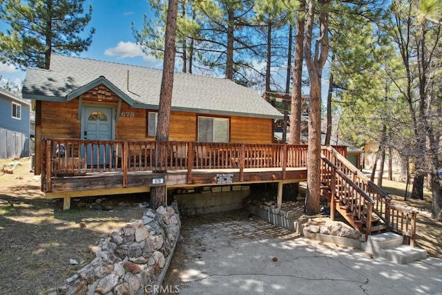 rear view of house featuring a wooden deck and a shingled roof