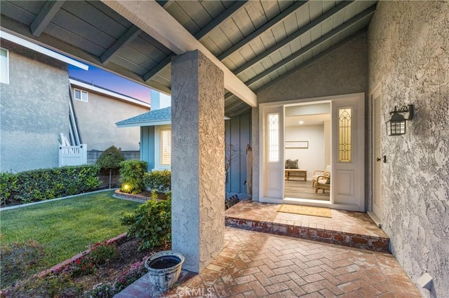 entrance to property featuring a lawn and stucco siding
