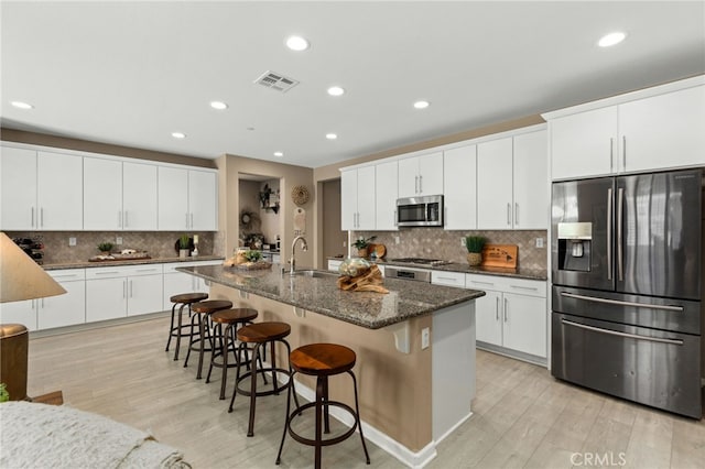 30525 Hawkscrest Rd, Murrieta, CA 92563 - kitchen with appliances with stainless steel finishes, a sink, tasteful backsplash, light wood finished floors, and a breakfast bar area