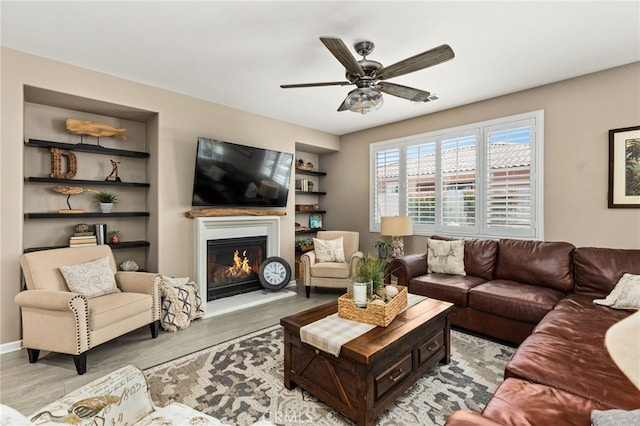 30525 Hawkscrest Rd, Murrieta, CA 92563 - living room with built in features, light wood-type flooring, a glass covered fireplace, and ceiling fan