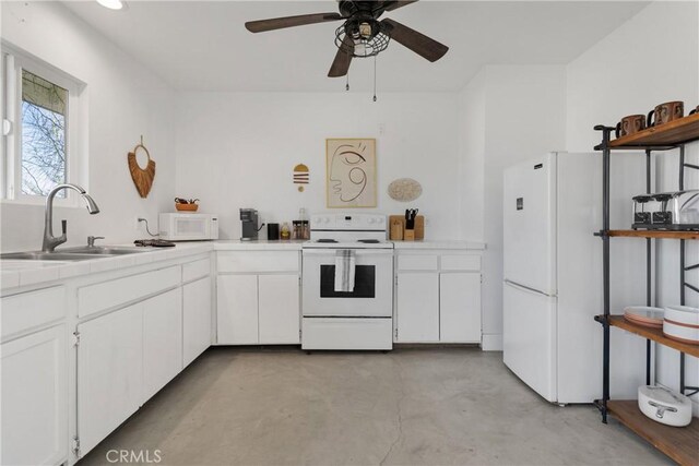 kitchen with white cabinets, a sink, concrete flooring, tile countertops, and white appliances