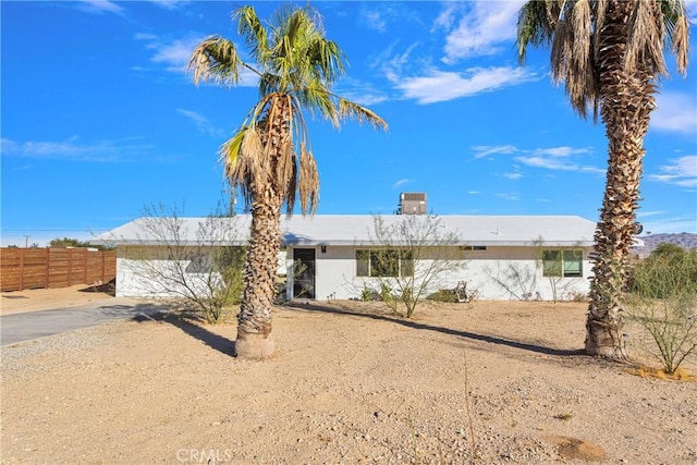 ranch-style home with a garage, central AC unit, driveway, stucco siding, and fence