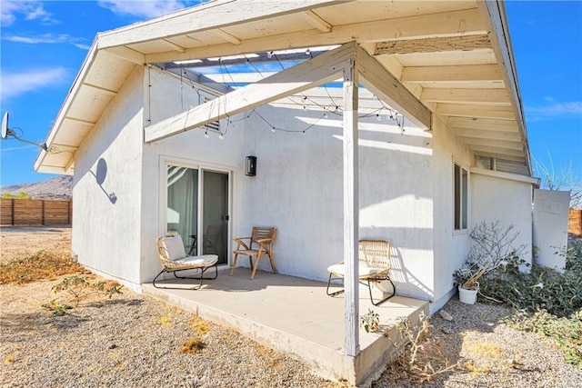 rear view of property with a patio, stucco siding, and fence