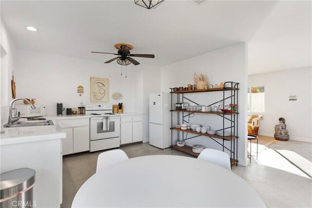 kitchen with white appliances, light countertops, finished concrete flooring, a sink, and white cabinetry