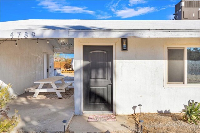 view of exterior entry with a patio and stucco siding