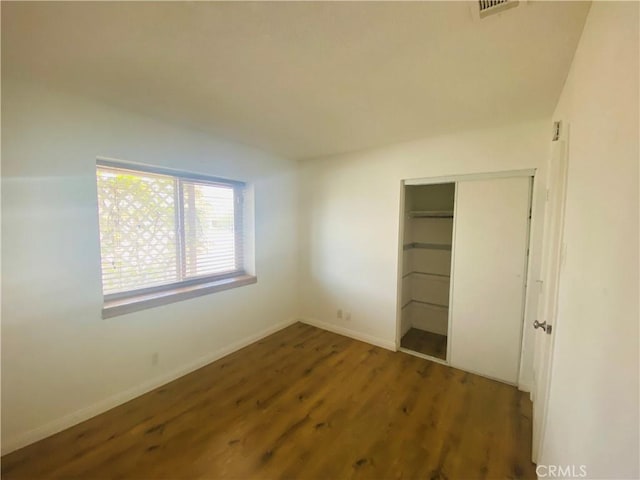 unfurnished bedroom with a closet, visible vents, wood finished floors, and baseboards