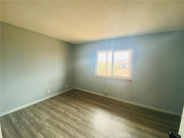 unfurnished room featuring a textured ceiling, wood finished floors, and baseboards