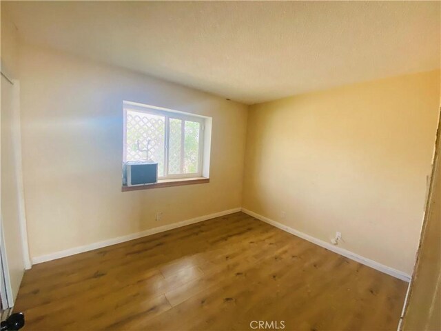 spare room featuring wood finished floors and baseboards