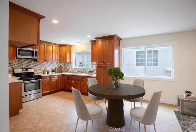 kitchen featuring stainless steel appliances, plenty of natural light, light tile patterned flooring, and decorative backsplash