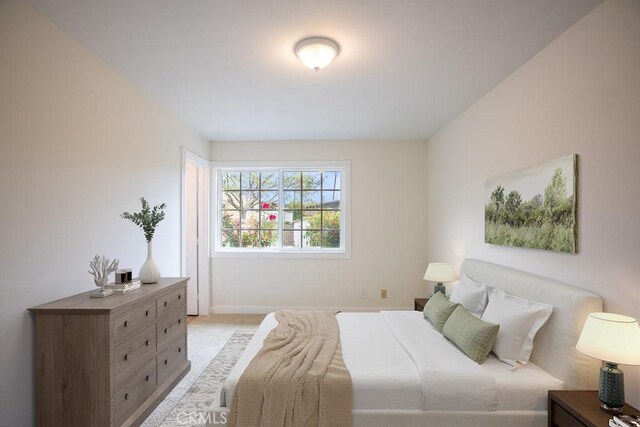 bedroom featuring light carpet and baseboards