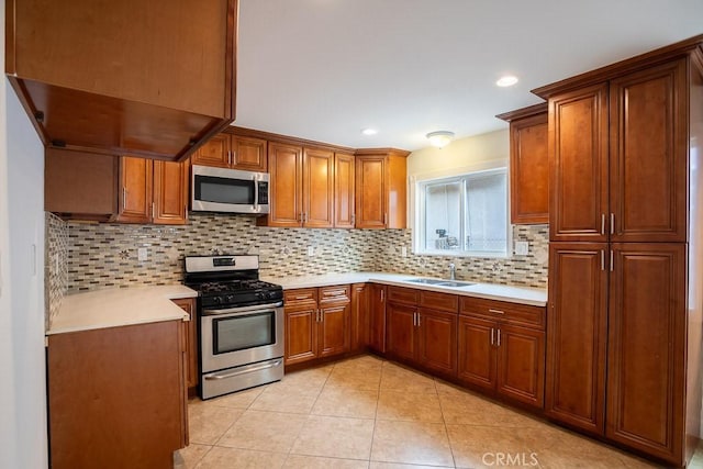 kitchen featuring a sink, decorative backsplash, stainless steel appliances, brown cabinetry, and light countertops