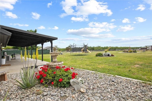 view of yard featuring a trampoline, a fenced backyard, and a patio area