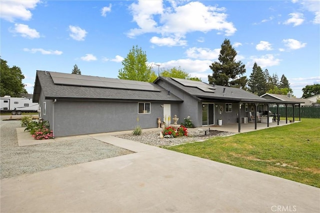 back of house featuring a patio, solar panels, stucco siding, and a yard