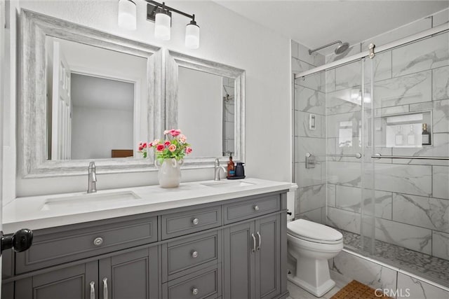 bathroom with a shower stall, toilet, double vanity, and a sink