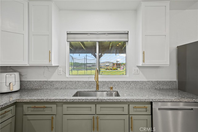 kitchen with light stone countertops, stainless steel dishwasher, decorative backsplash, and a sink