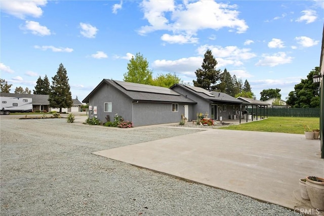 exterior space featuring stucco siding, fence, solar panels, a patio area, and a front yard