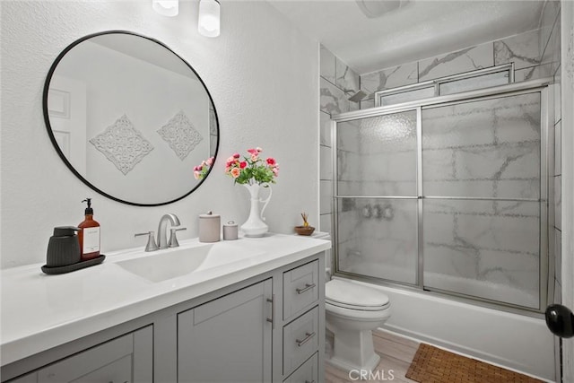 bathroom with toilet, wood finished floors, enclosed tub / shower combo, and vanity
