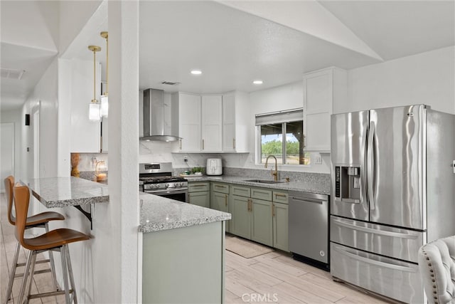 kitchen featuring wall chimney range hood, white cabinets, a sink, appliances with stainless steel finishes, and green cabinets