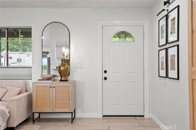 foyer featuring light wood-type flooring, plenty of natural light, and baseboards