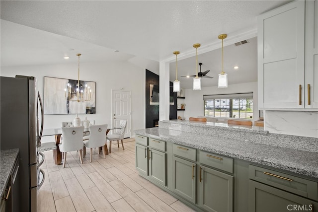 kitchen featuring visible vents, vaulted ceiling, pendant lighting, and freestanding refrigerator