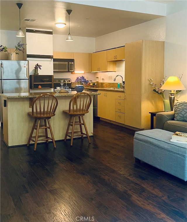 630 W 6th St Unit 611, Los Angeles, CA 90017 - kitchen with appliances with stainless steel finishes, dark wood finished floors, light brown cabinets, a kitchen island, and stone counters