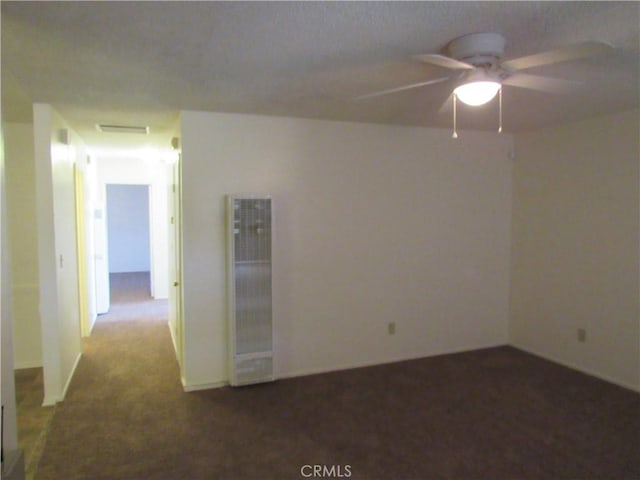 spare room featuring a heating unit, carpet, visible vents, and a ceiling fan