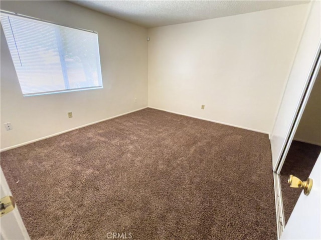 18225 Casaba Rd, Adelanto, CA 92301 - unfurnished room featuring baseboards, dark carpet, and a textured ceiling