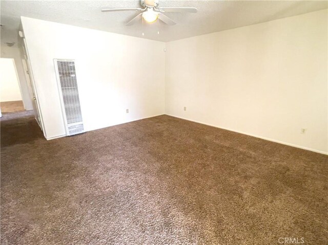 18225 Casaba Rd, Adelanto, CA 92301 - unfurnished room with dark colored carpet, a heating unit, and a ceiling fan
