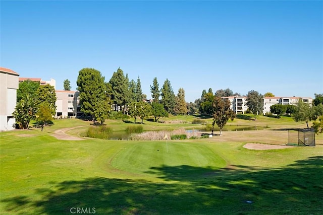 view of property's community with a lawn, a water view, and golf course view