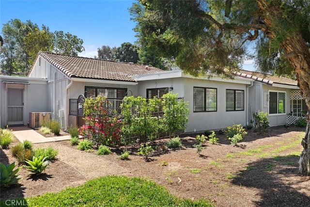 rear view of property featuring a tile roof and stucco siding