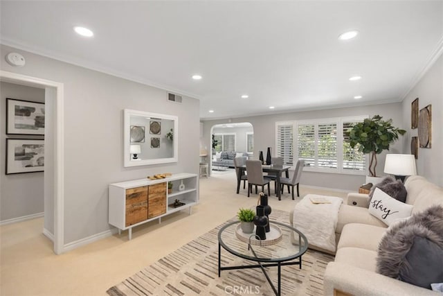 living room with arched walkways, baseboards, ornamental molding, light carpet, and recessed lighting