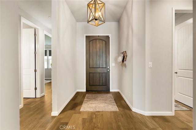 foyer entrance featuring dark wood finished floors, baseboards, and a notable chandelier