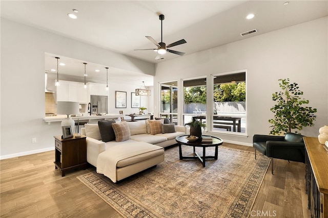 living room featuring baseboards, visible vents, ceiling fan, and light wood-style floors