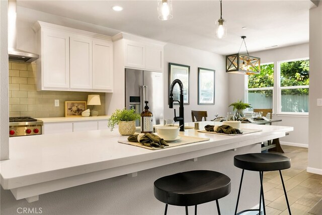 kitchen featuring hanging light fixtures, high end fridge, decorative backsplash, light countertops, and white cabinetry