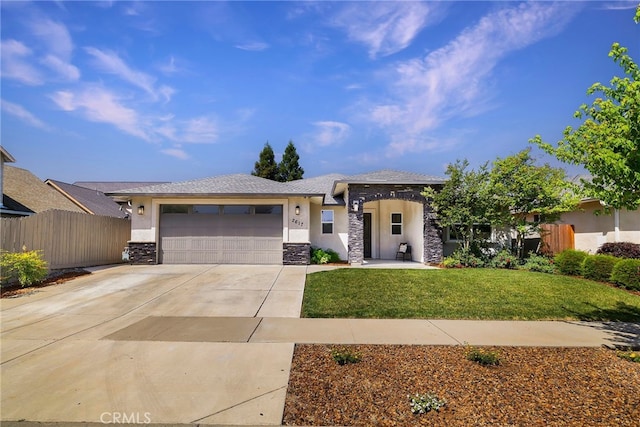 prairie-style house with stucco siding, fence, stone siding, concrete driveway, and an attached garage