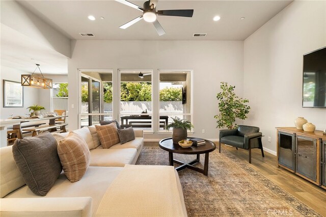 living room with wood finished floors, recessed lighting, visible vents, and ceiling fan with notable chandelier