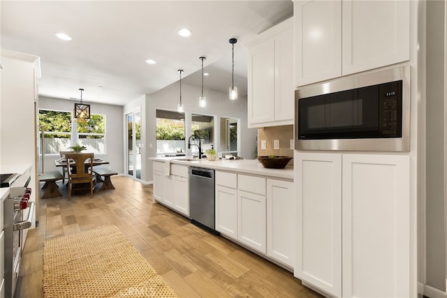 kitchen featuring recessed lighting, hanging light fixtures, white cabinets, and stainless steel appliances