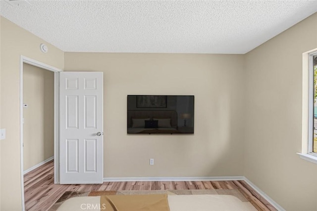interior space featuring a textured ceiling, wood finished floors, and baseboards