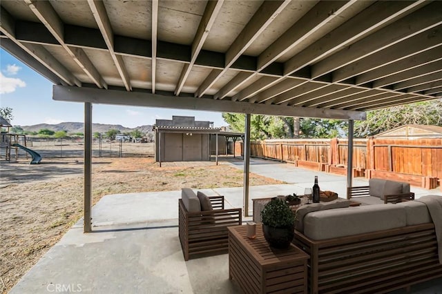 view of patio with a playground, a mountain view, an outdoor hangout area, and a fenced backyard