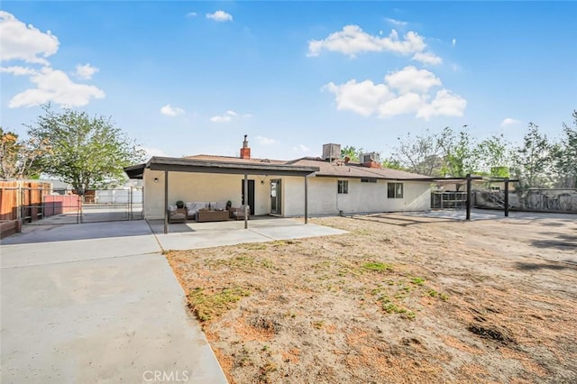 view of front of house featuring a chimney, a gate, fence, a patio, and outdoor lounge area