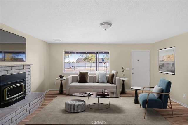 living room featuring a textured ceiling, visible vents, wood finished floors, and baseboards