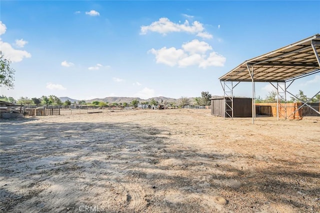 view of yard featuring an outbuilding, a mountain view, and fence