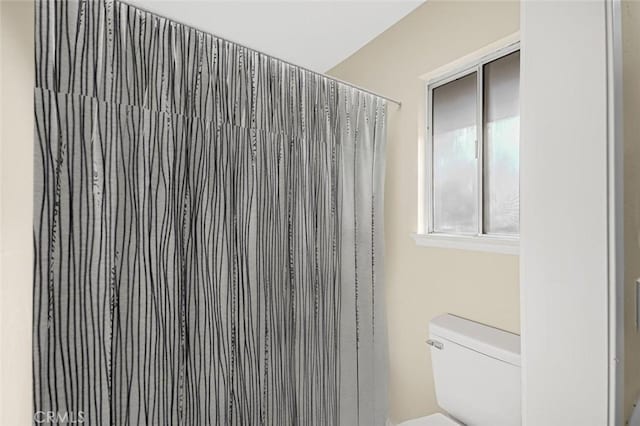 bathroom with a shower with shower curtain and toilet