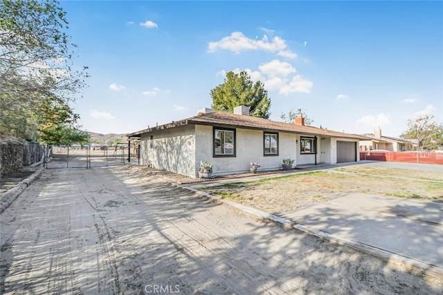 ranch-style house with a garage, a gate, a chimney, stucco siding, and fence