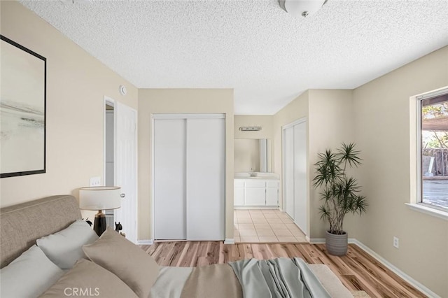 bedroom with a textured ceiling, wood finished floors, and ensuite bath