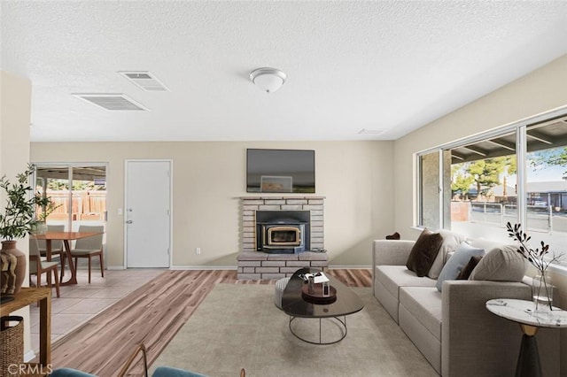living area with a textured ceiling, visible vents, and light wood-type flooring