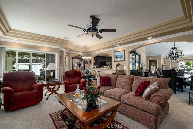 living room featuring crown molding, arched walkways, a raised ceiling, ceiling fan with notable chandelier, and carpet flooring