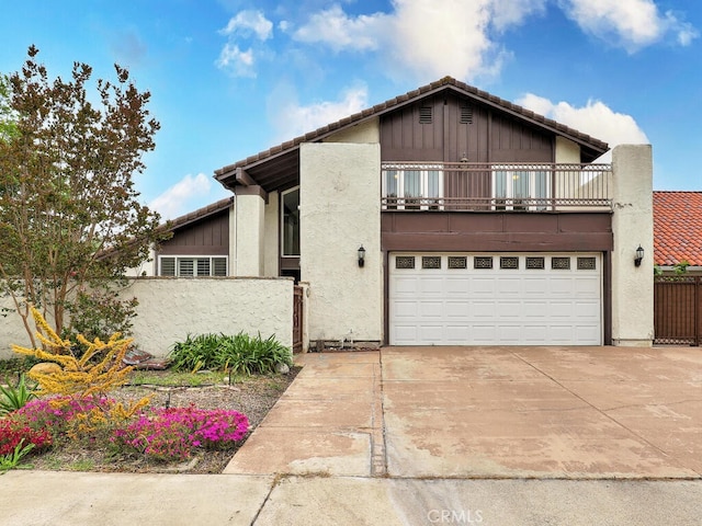 view of front of home featuring driveway, a balcony, stucco siding, fence, and a garage
