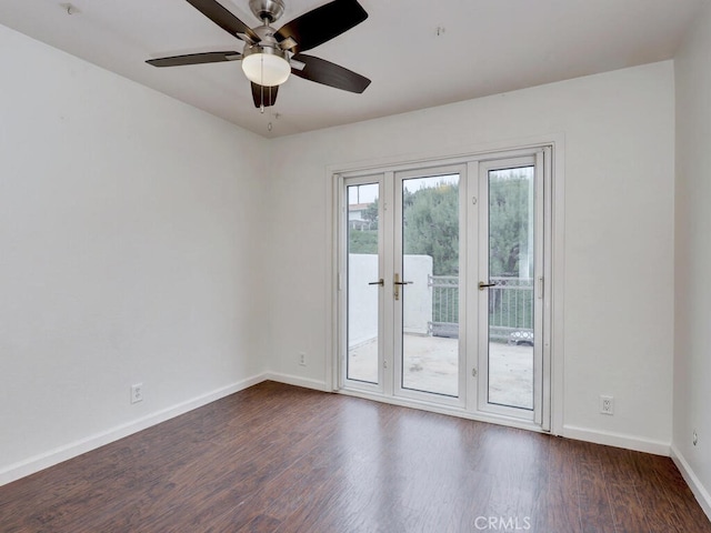 spare room with dark wood-style flooring, a ceiling fan, and baseboards